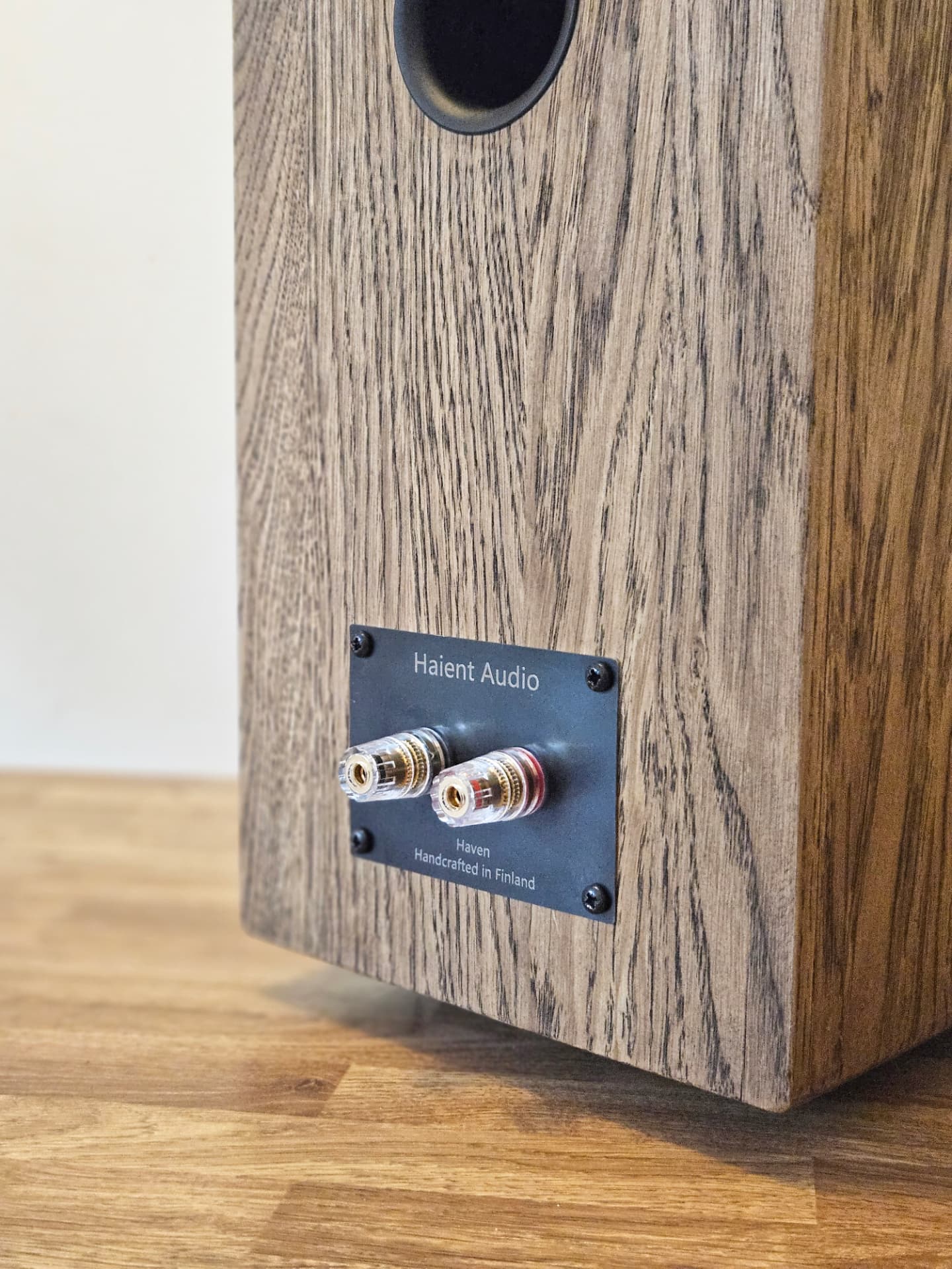 Rear connection panel of a Haient Haven loudspeaker in dark oak, with binding posts and Handcrafted in Finland engraving