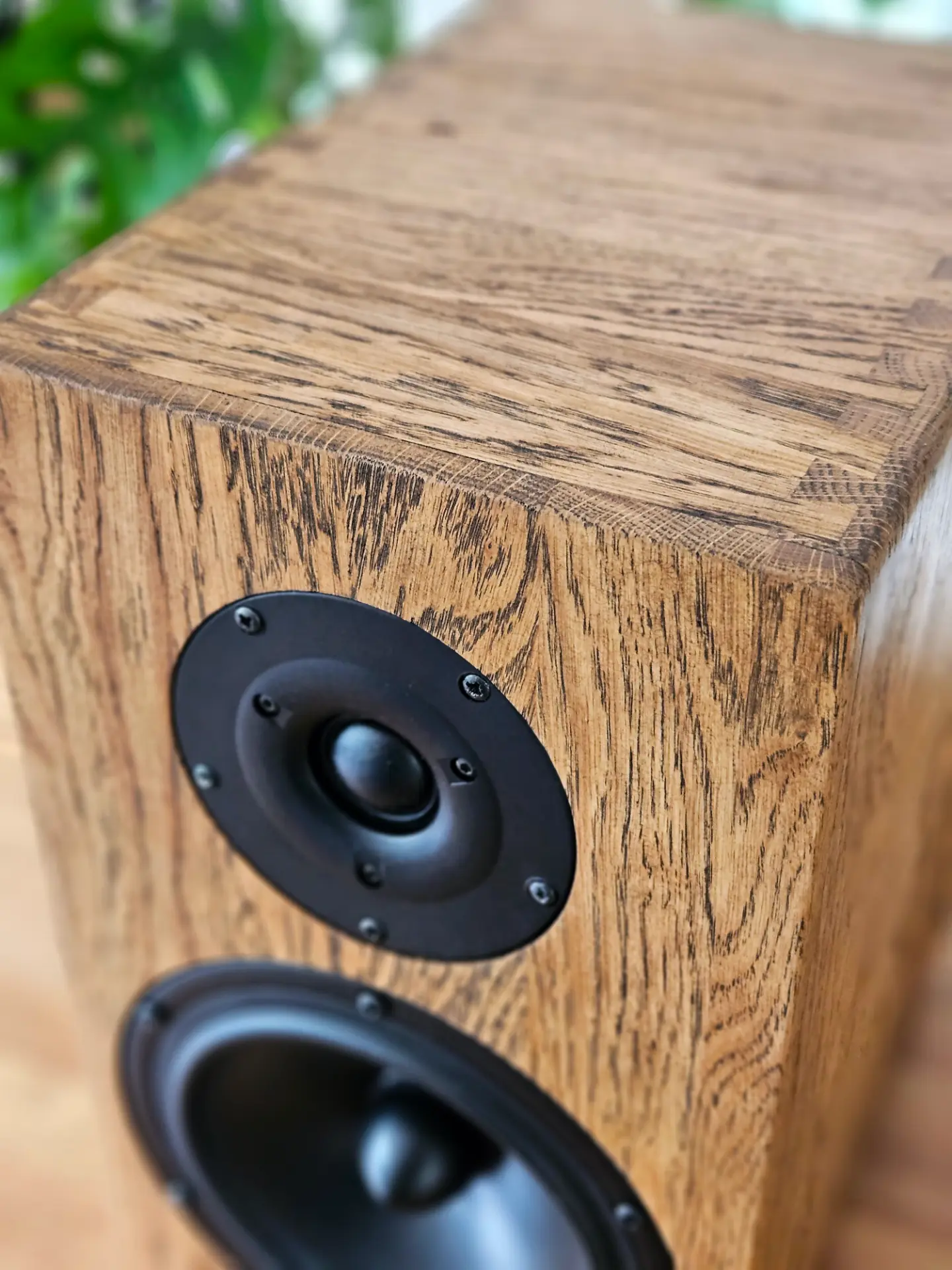 Solid oak Haient loudspeaker on a dark concrete floor